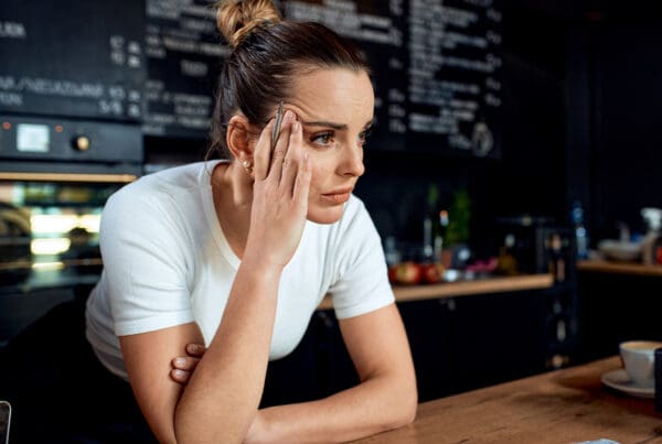 Business Interruption Insurance - Portrait of a Frustrated Small Business Owner Standing at the Counter of Her Closed Cafe